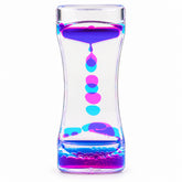 Use only descriptions that match the image shown: Lava Flow Sensory Desktop Toy with colourful bubbles; Clear acrylic liquid-motion sensory toy; Complementary coloured droplets flowing through the Lava Flow toy; Lava Flow Sensory Desktop Toy on an office desk; Liquid-motion toy in a study space; Lava Flow Sensory Desktop Toy retail displayer of 12; Individually boxed Lava Flow Sensory Desktop Toy.
