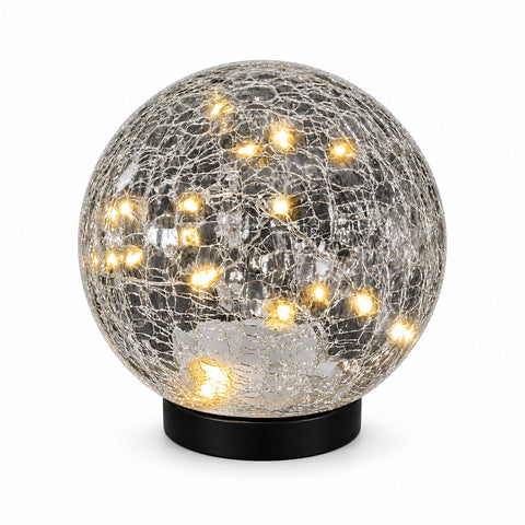 Use only descriptions that match the image shown: Solar Faerie LED Globe with detachable garden stake; Hand-blown crackle glass solar globe; Solar Faerie LED Globe illuminated at dusk; Crackle glass globe displayed in a garden; Solar LED globe on a patio table without its stake; Close-up of the Solar Faerie LED Globe crackle glass; Medium Solar Faerie LED Globe, 15 cm diameter.