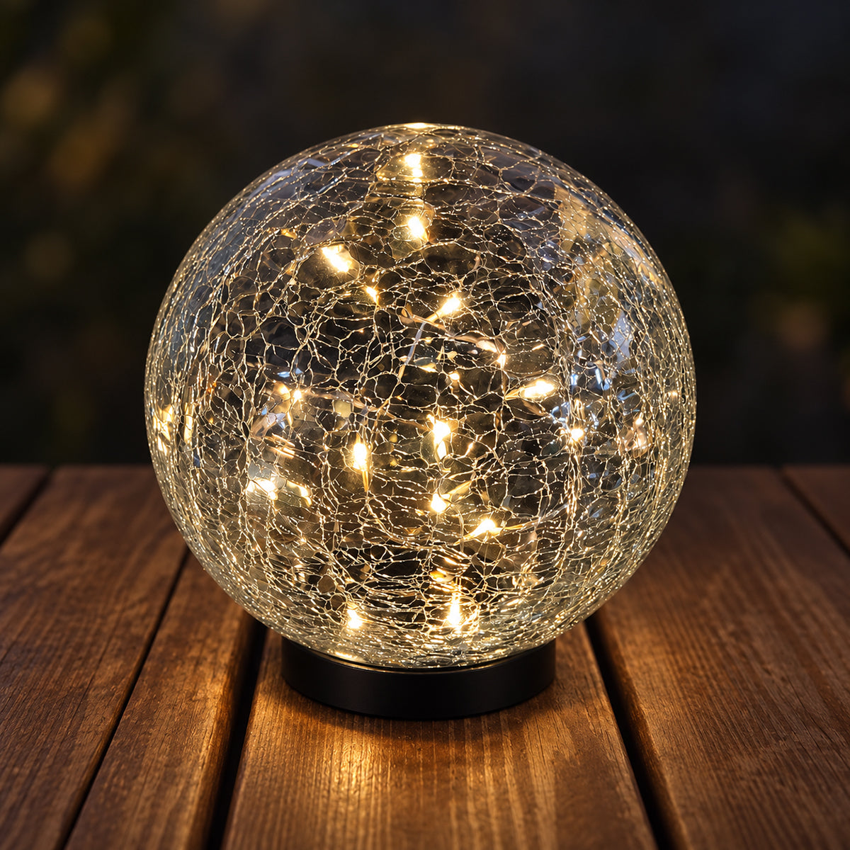 Use only descriptions that match the image shown: Solar Faerie LED Globe with detachable garden stake; Hand-blown crackle glass solar globe; Solar Faerie LED Globe illuminated at dusk; Crackle glass globe displayed in a garden; Solar LED globe on a patio table without its stake; Close-up of the Solar Faerie LED Globe crackle glass; Medium Solar Faerie LED Globe, 15 cm diameter.