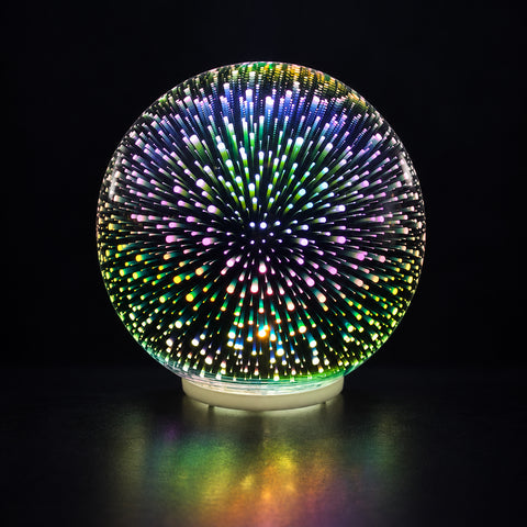 Use only descriptions that match the image shown: 3D Faerie LED Globe with multi-colour illumination; Glass 3D Faerie LED Globe with the light switched off; Illuminated 3D Faerie LED Globe on a mantel; Battery-operated Faerie globe light on a desktop; 3D Faerie LED Globe displayed on a patio table; Bottom ON/OFF switch on the 3D Faerie LED Globe; Medium 3D Faerie LED Globe, 15 cm diameter